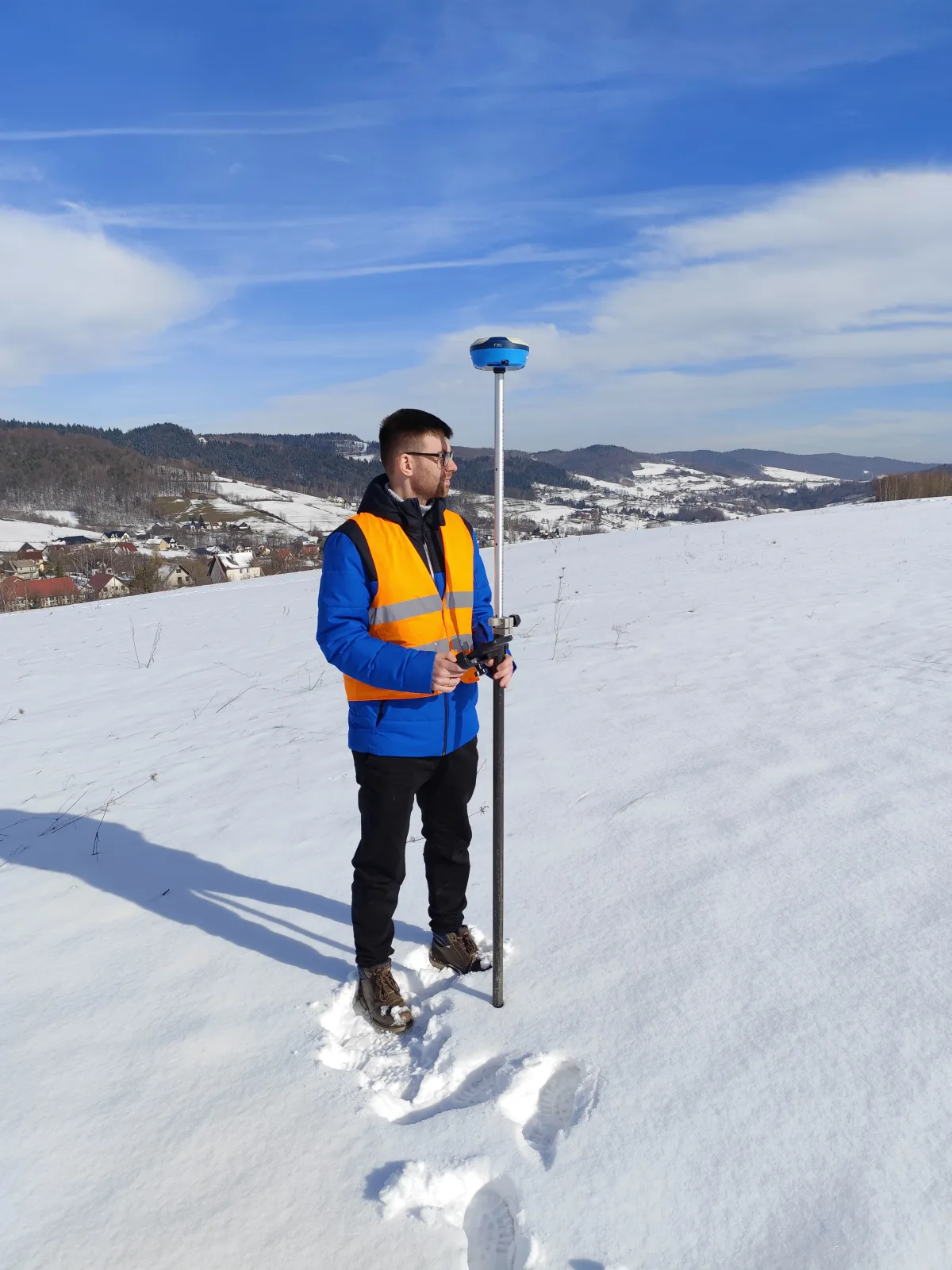 Geodeta GeoDuet z odbiornikiem GNSS podczas zimowego pomiaru