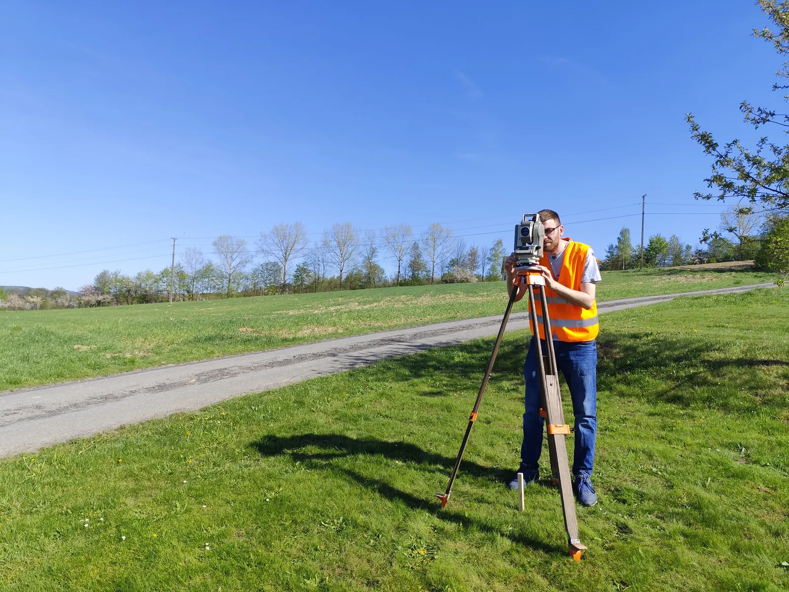 Geodeta GeoDuet wykonuje pomiar przy drodze na otwartym terenie